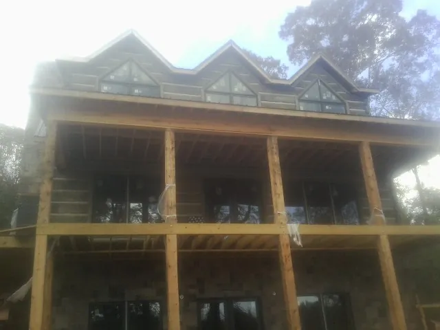Dormers and porch framing on a large log home under construction — Roof Coating work by our crew in Hitchcock