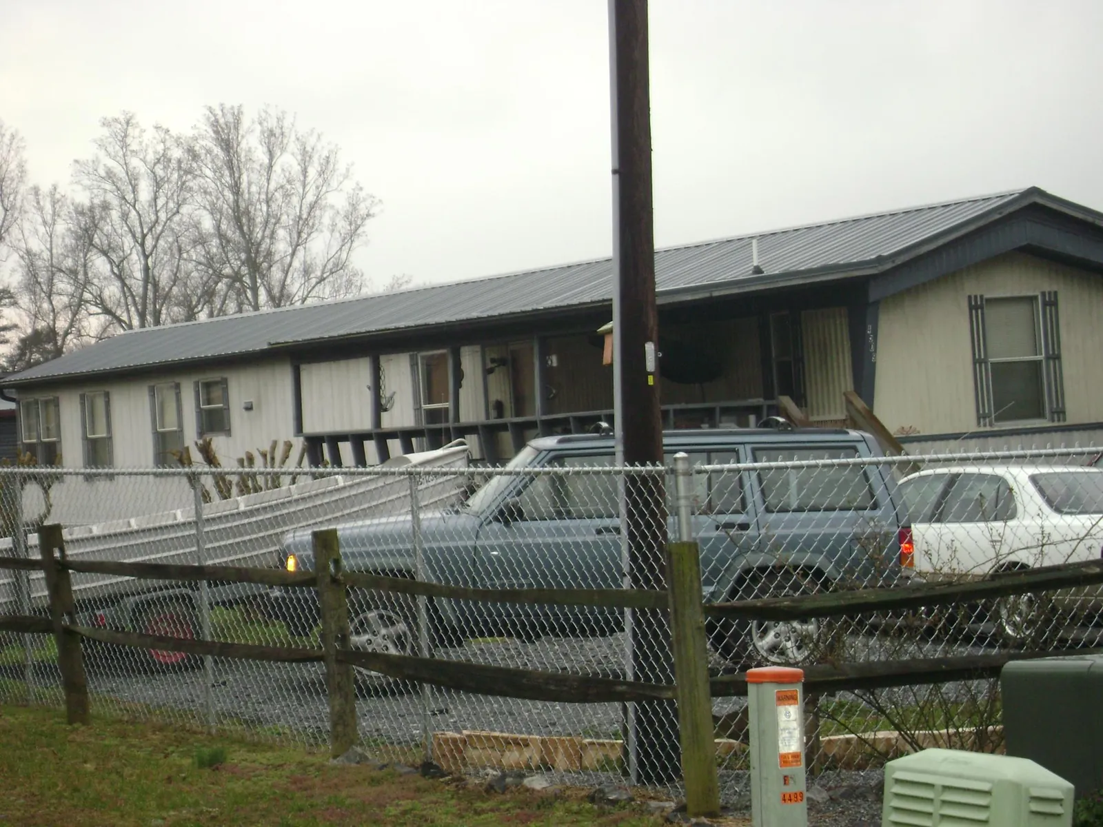 Dark metal roof on a long single story building behind a chain link fence in Hitchcock