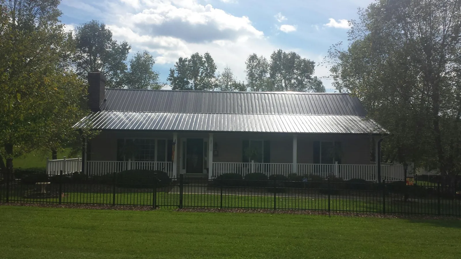 Gray metal roof on a brick ranch with a full width front porch — Gutter Guard Installation work by our crew in Hitchcock