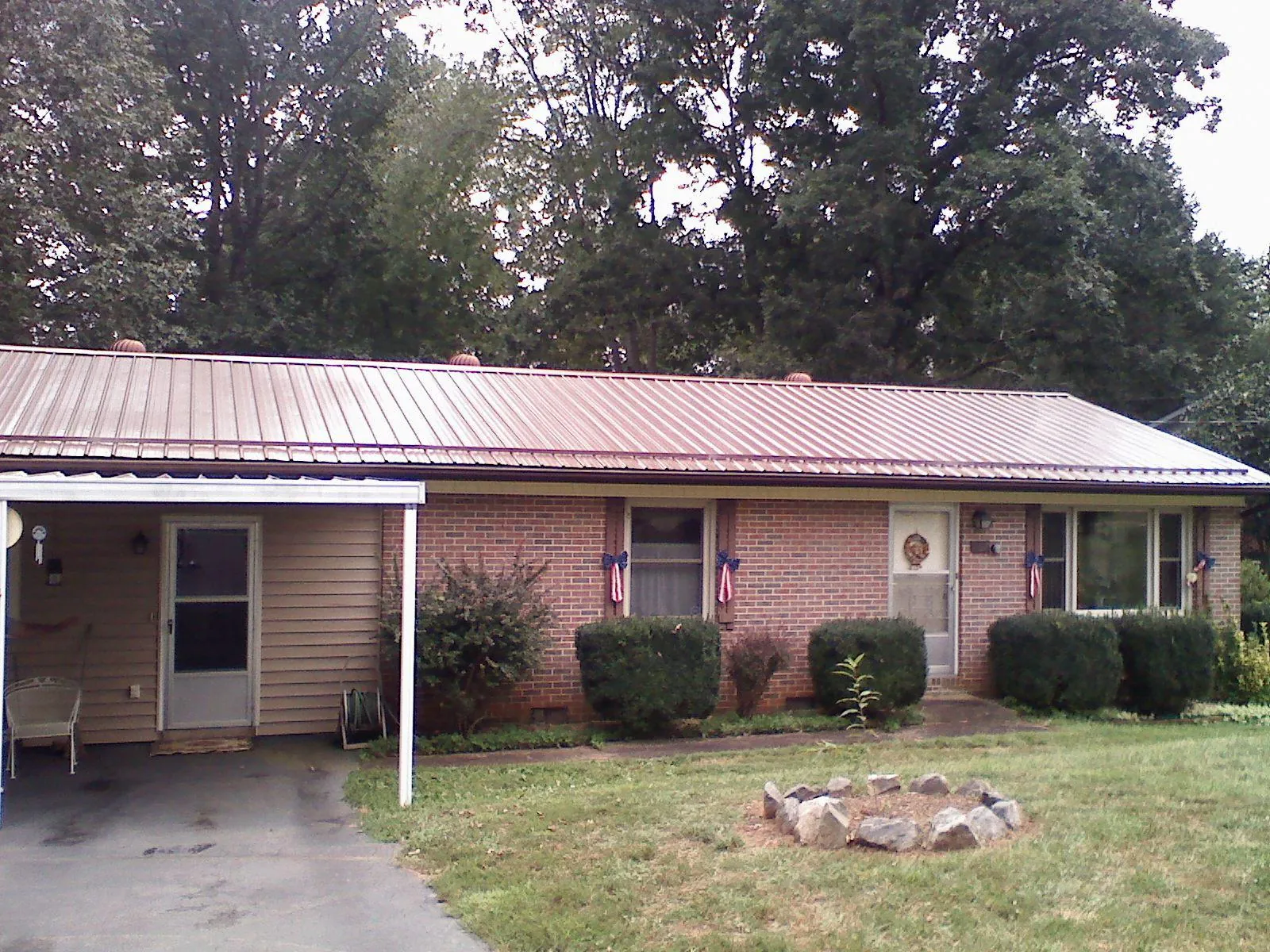 Bronze metal roof and carport on a brick ranch home — Roof Repair work by our crew in Hitchcock