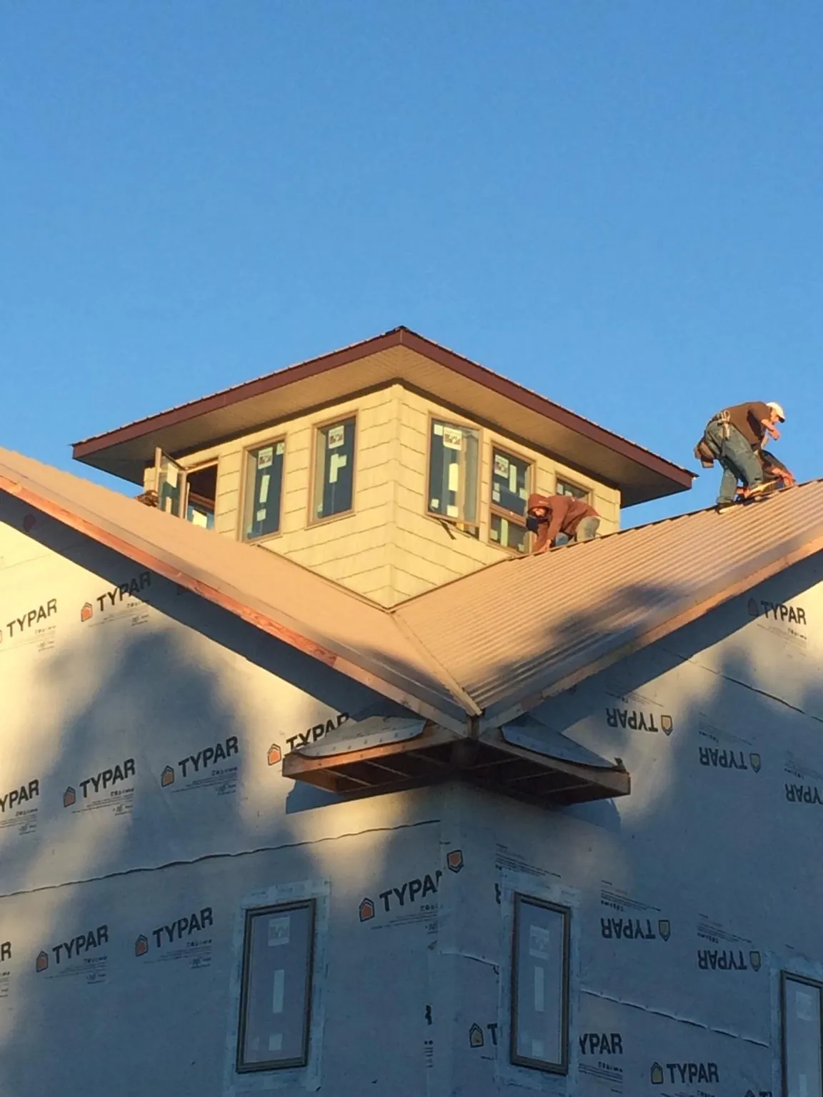 Roofers working around a rooftop cupola on a new metal roof at sunset — Roof Waterproofing in Hitchcock by Roofing Brothers